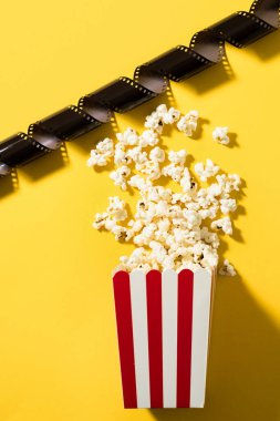Klasik çizgili kova, lezzetli patlamış mısır ve sarı arka planda film stoku..