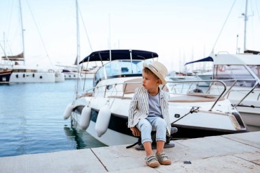 Marinadaki yatın yanındaki rıhtımda oturan şirin şık çocuk..