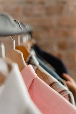 Çeşitli erkek gömlekleriyle ahşap askılarda asılı duran askılar.