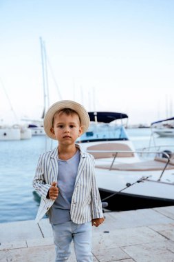 Marinada yatın yanında poz veren yakışıklı bir çocuğun portresi.