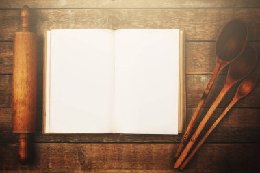 Masanın üzerinde çeşitli ahşap mutfak aletleri ve klasik yemek kitabı var..