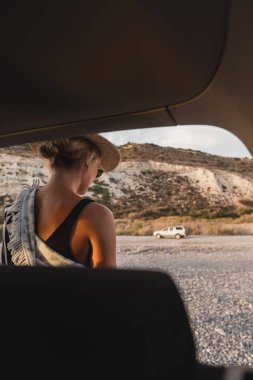 Gezgin kadın, çakıl taşı plajında arabasının yanında mola veriyor..