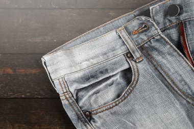 Ahşap arka planda düğmesiz kot pantolona yakın plan