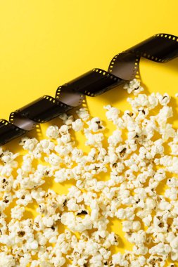 Sarı arka planda lezzetli patlamış mısır ve film stoku..