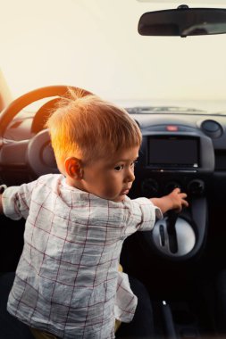 Arabada oynayan sevimli küçük bir çocuk ve gerçek bir yetişkin gibi davranıyor..