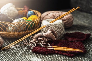Çeşitli yün iplik ve örgü aletleriyle dolu sepet..