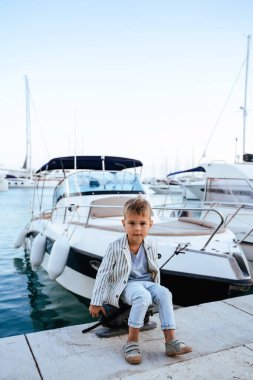 Marinadaki yatın yanındaki rıhtımda oturan şirin şık çocuk..