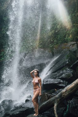 Muhteşem, ıslak kadın Kamboçya 'da Phnom Kulen şelalesinin yanında poz veriyor.