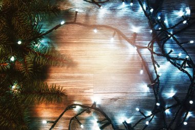 Tahta yüzey pırıl pırıl Noel ışıkları ve taze ladin dallarıyla süslenmiş..