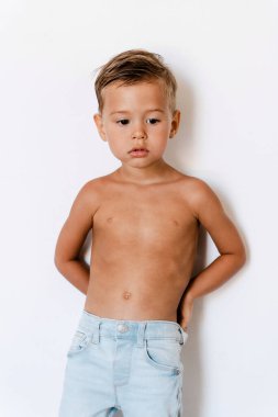 Modeller gibi beyaz arka planda poz veren kot pantolon giyen sevimli küçük çocuk..