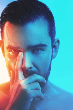 Mavi ve turuncu ışıkta ıslak yüzlü yakışıklı genç adamın portresi.