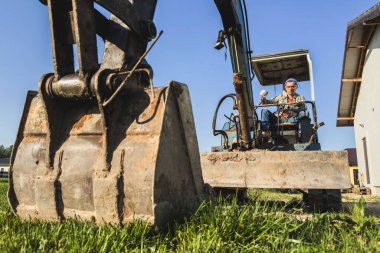 Delikanlı, inşaat alanında çalışırken eski kazıcısını çalıştırıyor..