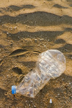 Plastik şişenin kumsala yakın çekimi. Plastik atık kirliliği.