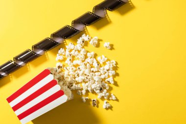 Klasik çizgili kova, lezzetli patlamış mısır ve sarı arka planda film stoku..
