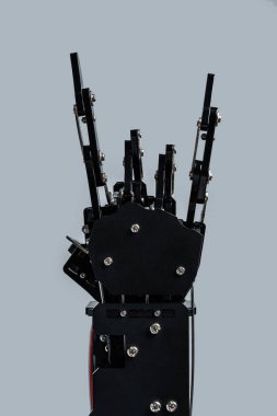 Gerçek robotik el, gri arkaplana karşı boynuzların işaretini verir..