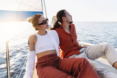Genç ve çekici bir çift denizde yelkenli sürerken dinleniyor..