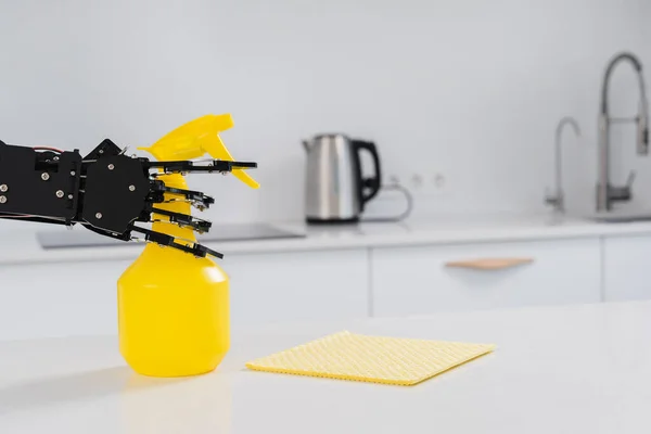 Real robot's hand with spray cleaner in white kitchen. Concept of  robotic process automation.