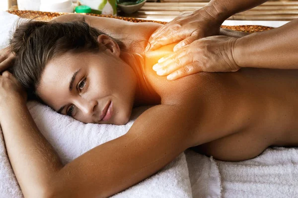 Young woman during healing back massage therapy in Asian traditional clinic