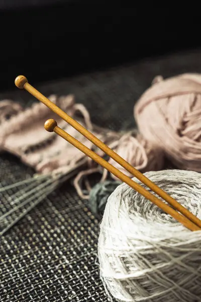 Closeup of woolen threads and wooden knitting needles.