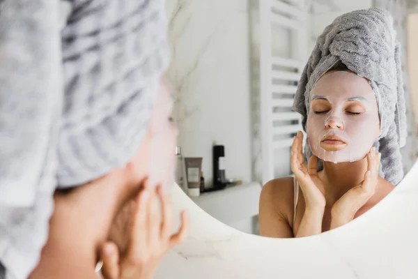 Banyoda Yüzünde Uygulamalı Çarşaf Maskesi Olan Güzel Bir Kadın Aynaya — Stok fotoğraf