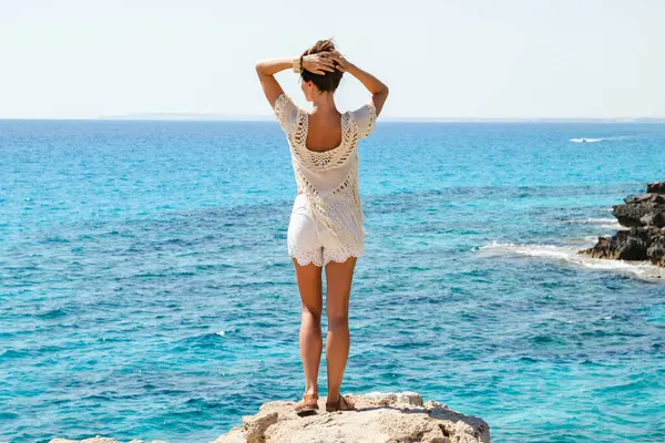 彼女が崖の端に立っているとして有名なケープグレコの視点からの素晴らしい景色を見ている若い女性 — ストック写真