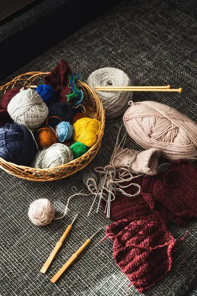 Basket with various woolen thread and knitting tools.