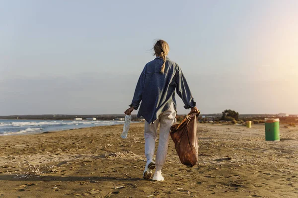 女性志愿者正在海滩上收集塑料垃圾 为保持自然清洁做出贡献 图库照片