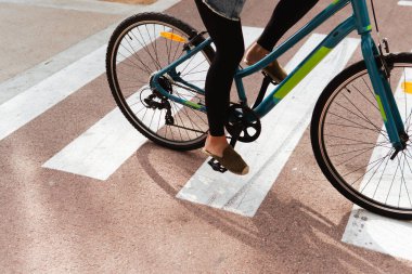 Bisikletle yaya geçidinden geçen bir kadının ayaklarının yakın görüntüsü..