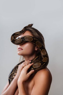 Yüzünde piton yılanı olan genç bir kadın gözlerini kapatıyor.