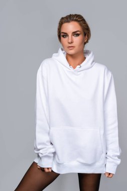 Beyaz, büyük kapüşonlu, boş bir yeri olan, gri arka planı olan bir kadın..