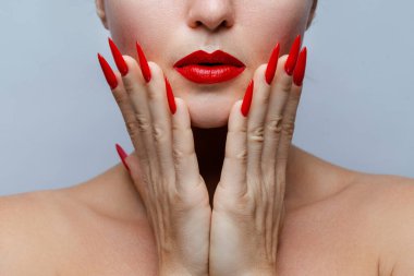 Kırmızı Stiletto Çivileri ve Uyumlu Ruj ile Kadının Yüzüne Yakın Çekim.