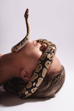 Yüzünde piton yılanı olan genç bir kadın gözlerini kapatıyor.