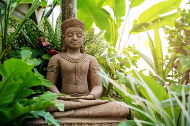 Bahçede Tropikal Yapraklarla Oturan Buda Heykeli.