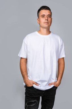 Büyük beyaz tişörtlü bir adam. Boş alanı var. Model için ideal, gri arka planda..