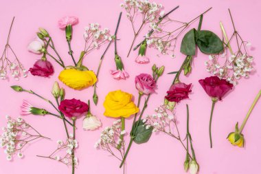 Neşeli bir görüntü için pembe bir zemine yayılmış canlı çiçekler..