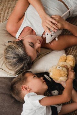 Mother and Little Son Playing Together with Stuffed Toys on the Floor at Home. clipart