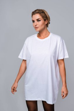 Beyaz tişörtlü bir kadın. Boş yeri var. Model için ideal, gri arka planda..