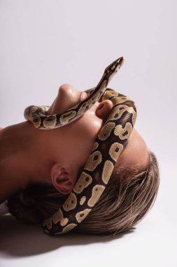 Yüzünde piton yılanı olan genç bir kadın gözlerini kapatıyor.