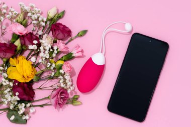 Modern samimiyet, pembe çiçekli akıllı telefonun yanında bir vibratör ve yetişkin oyuncağı sergilemek..