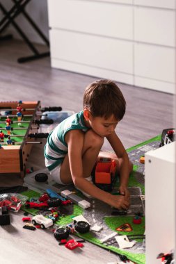 Neşeli çocuk, güneşli modern bir odada oyuncaklarıyla oynuyor..