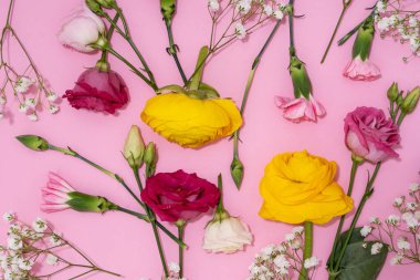 Neşeli bir görüntü için pembe bir zemine yayılmış canlı çiçekler..