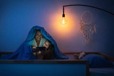 Anne ve oğlu gece birlikte akıllı telefon izliyorlar..