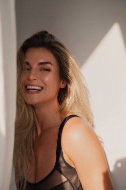 Beyaz Duvara Karşı Siyah Giysili Gülümseyen Sarışın.