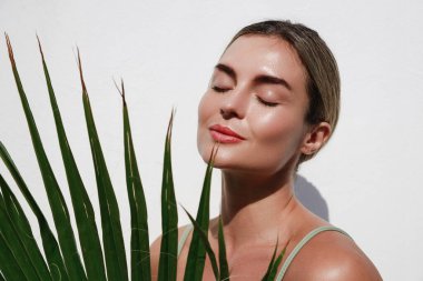 Beyaz arka planda Palm Leaf 'li Güzel Genç Kadın Portresi.