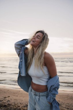 Genç Tarz Kadını Sahilde Günbatımının tadını çıkarıyor.