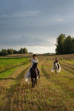 Güneş Işığı Tarlası 'nda Atlara Binen Şık Giyimli İki Kadın.