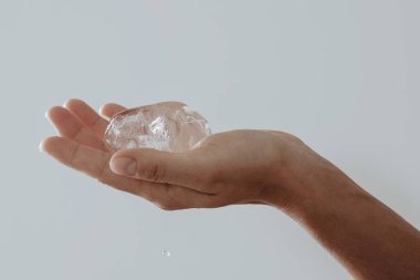 Yakın plan, temiz bir buz parçasını nazikçe tutuyor..