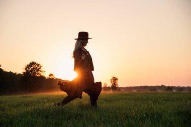 Günbatımında Deri Ceket ve Şapka Giyen Tasasız Kadın.
