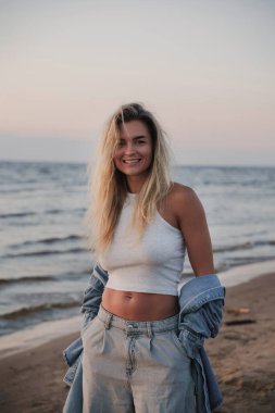 Genç Tarz Kadını Sahilde Günbatımının tadını çıkarıyor.