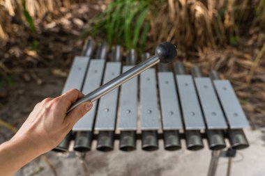 Female hand with mallet and outdoor metal xylophone.  clipart